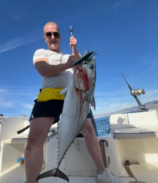 Angler lifting a freshly caught tuna on board with Fishing Trips Málaga