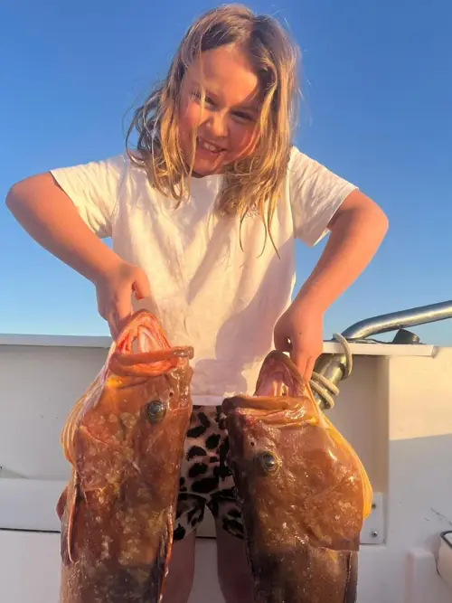 Smiling girl showing two fish caught during a fishing trip in Málaga