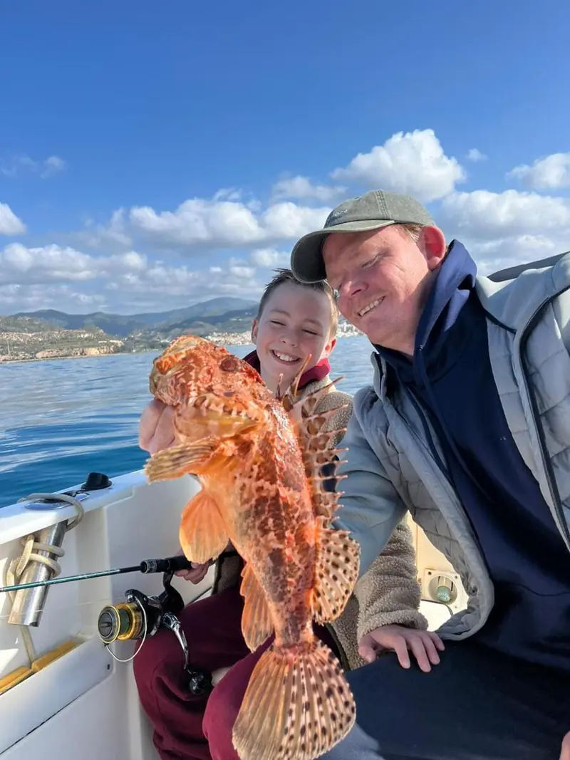 Father and son showing their catch during a fishing trip in Málaga