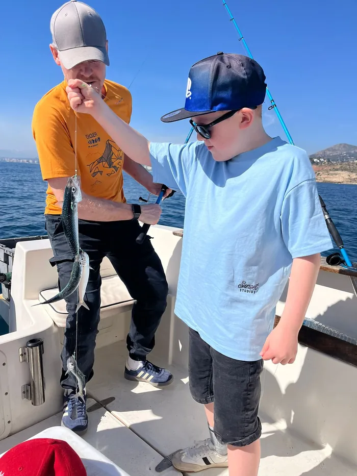 Boy landing his first catches with his father on a fishing trip in Málaga