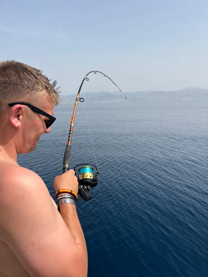Angler with a bent rod fighting a fish on a boat fishing trip in Málaga