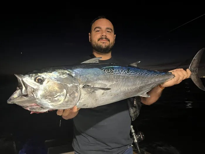 Angler holding a tuna caught at night during a tuna fishing trip in Málaga