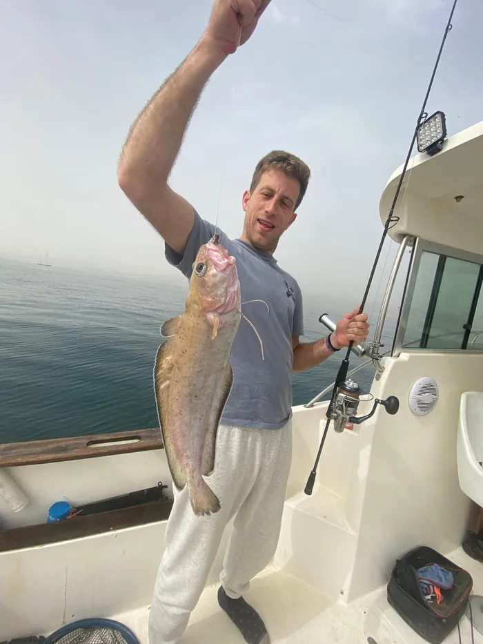 Angler showing a bottom fishing catch on board the boat in Málaga