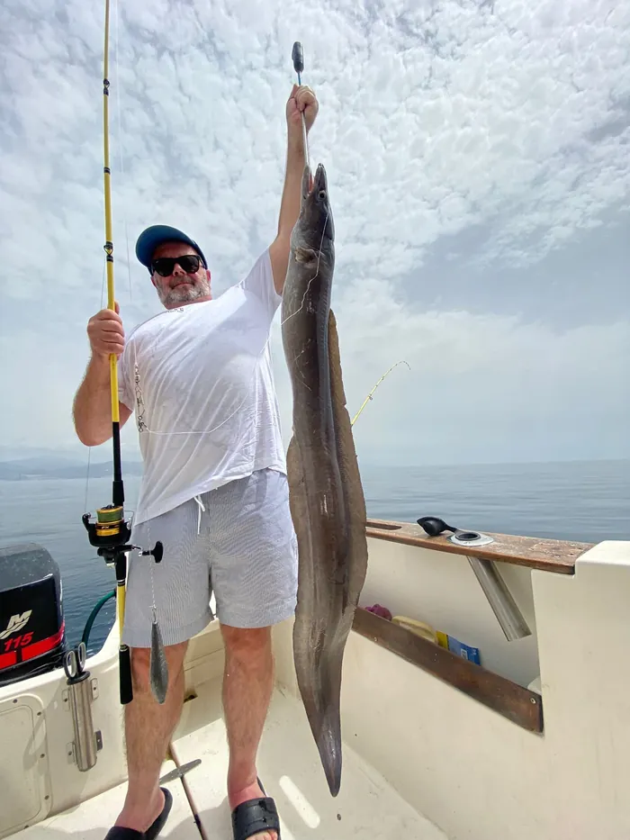 Angler showing a conger eel caught on board with Fishing Trips Málaga
