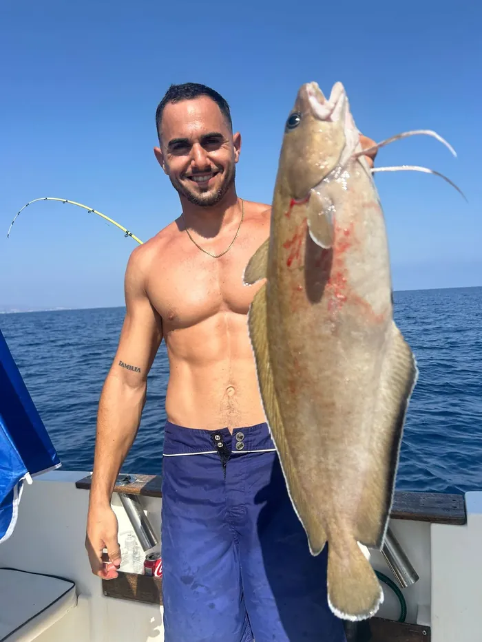 Smiling angler showing a big catch on a fishing trip in Málaga