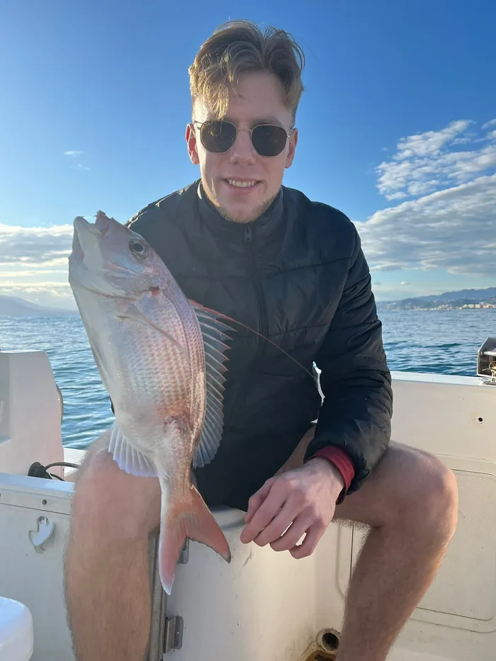 Angler sitting on board showing a sea bream caught with Fishing Trips Málaga